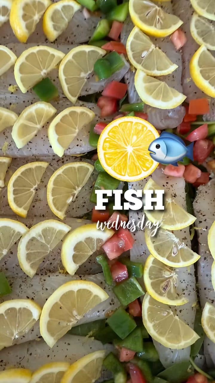 Fresh fish fillets baking with lemon, peppers, and tomato