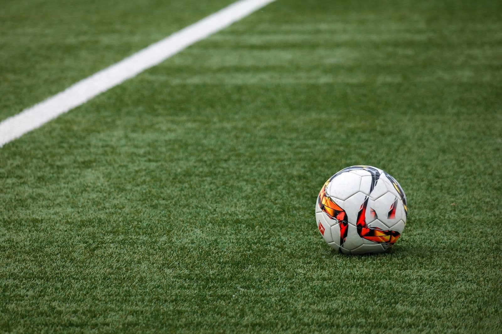 A soccer ball on the pitch beside a sideline